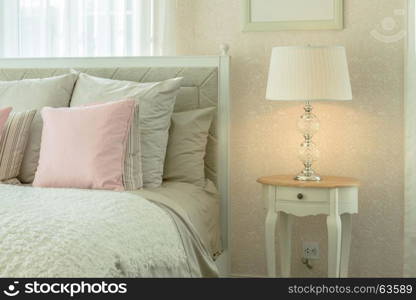 cozy bedroom interior with pink pillows and reading lamp on bedside table