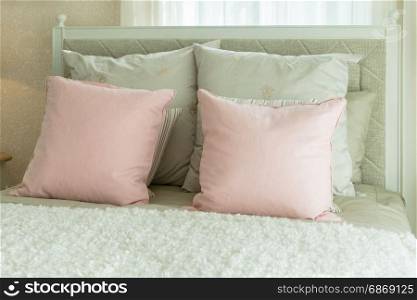 cozy bedroom interior with pink pillows and reading lamp on bedside table