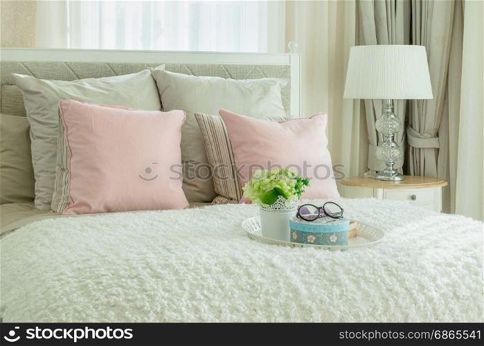 cozy bedroom interior with pink pillows and white tray of flower on bed