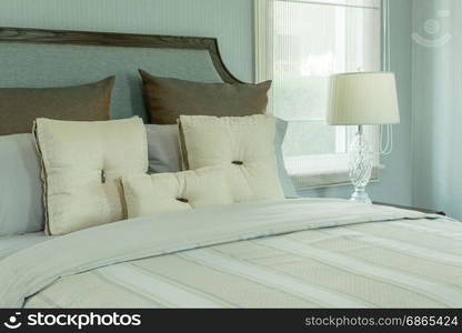 cozy bedroom interior with white pillows and reading lamp on bedside table