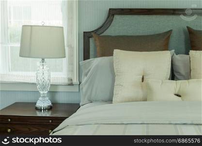 cozy bedroom interior with white pillows and reading lamp on bedside table