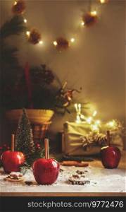 Cozy Christmas background with event fairy light, red apples with cinnamon sticks , gift box, garland and holiday decoration.