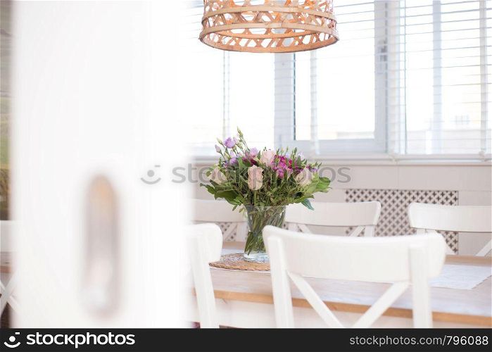 cozy dining room interior with flower decoration in a white room of a modern house close-up colorful. cozy dining room interior with flower decoration in a white room of a modern house close-up
