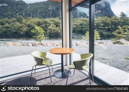 Cozy living room or restaurant interior design with nature scenic windows view. Green environment lifestyle. Chair and table interior with mountain scenery. Modern Australian design living room.