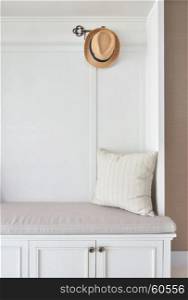 Cozy seat with white frame with striped pillow and panama hat