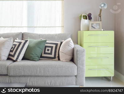 Cozy sofa with geometric pattern pillows and green sideboard in living corner