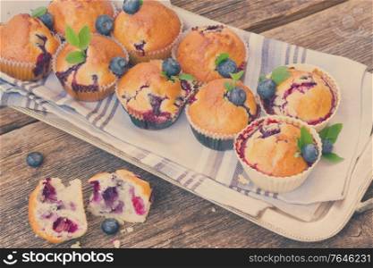 cplate of upcakes with fresh blueberry berry and leaves on wooden table, retro toned. cupcakes with blueberry