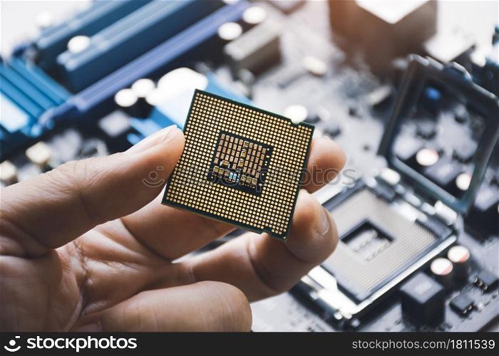 CPU processor chip in technician hand and computer motherboard background