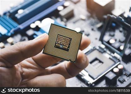 CPU processor chip in technician hand and computer motherboard background