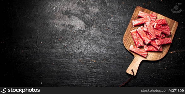 Crab meat on a wooden cutting board. On a black background. High quality photo. Crab meat on a wooden cutting board.