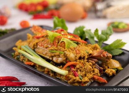 Crab stir-fried curry powder on a black plate on the cement floor.