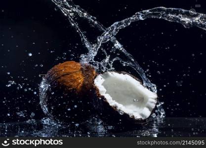 cracked coconut with big splash on black background. cracked coconut