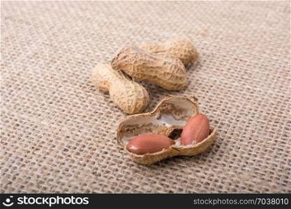 Cracked open peanuts with shell on a linen canvas background
