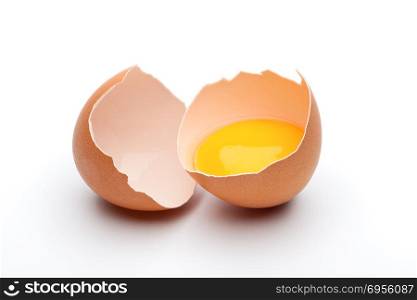 Cracked raw brown egg, egg yolk in egg shell on white background