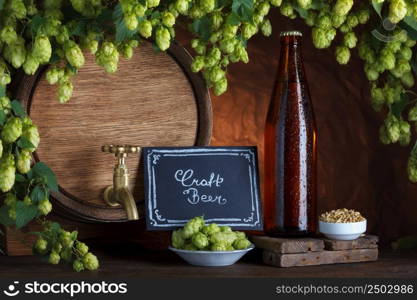 Craft bottled beer with beer barrel and fresh hops with barley for brewing still-life