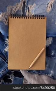 Craft notebook at jeans denim as background texture. Blue jeans fabric on table