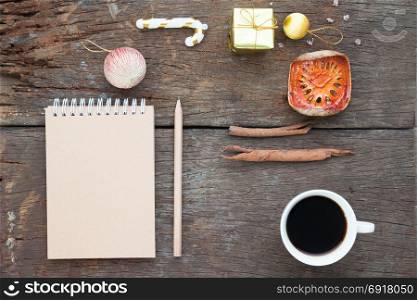 Craft notebook, pencil, cup of coffee and Christmas ornaments on antique wooden table, Flat lay