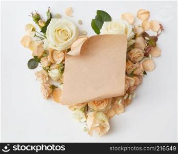 crafting a piece of paper at the heart of roses isolated on white , flat lay. Roses buds as heart