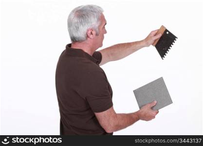 craftsman holding a tile and a tool