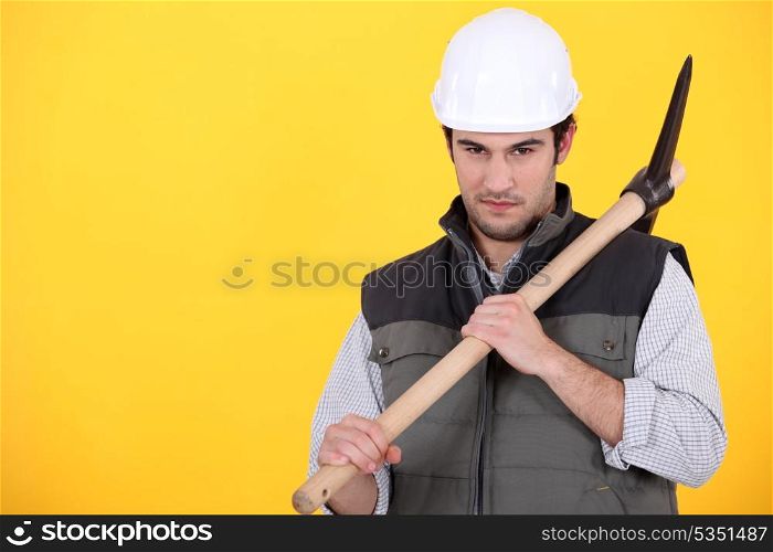 craftsman holding pickaxe against yellow background