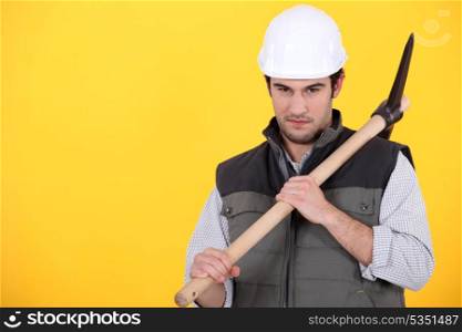 craftsman holding pickaxe against yellow background