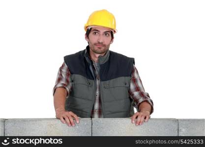 craftsman leaning on a stone block wall