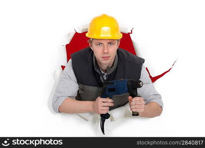 craftsman posing in the hole of paper wall and holding a drill