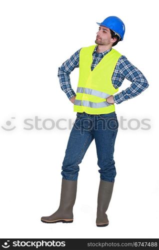 craftsman wearing hard hat standing with arms akimbo