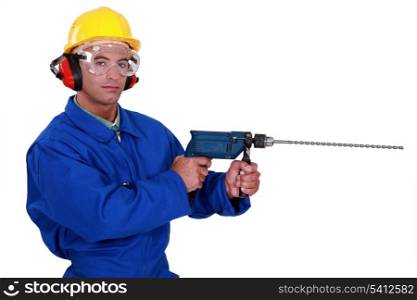 craftsman with earmuffs and protective goggles holding electric drill