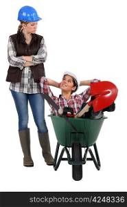 craftswoman accusing her lazy colleague for sitting in a wheelbarrow