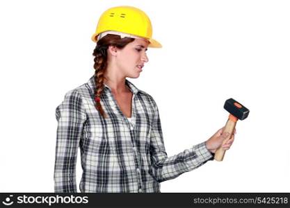craftswoman holding a hammer looking fed up