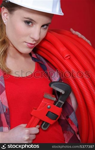 craftswoman holding a spanner and a hose