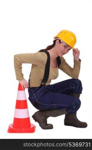 craftswoman kneeling next to a traffic cone