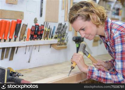 craftswoman working with chisel and hammer in her workshop