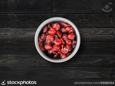 Cranberries in a bowl on a kitchen table. Black wood Background. Top view. Cranberries in a bowl on a kitchen table