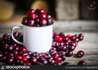 Cranberries on a mug on rustic wooden background