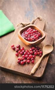 Cranberry jam in a wooden bowl on a wooden background