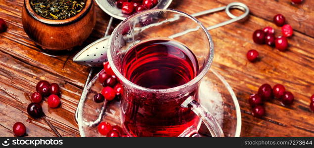 Cranberry tea in a glass cup on wooden table. Berry tea on wooden table