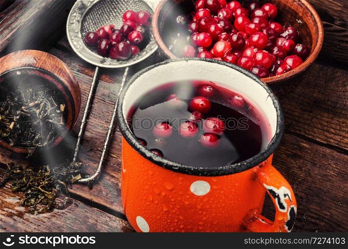 Cranberry tea in a glass cup on wooden table. Hot drink with cranberries