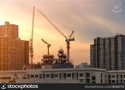 Crane and construction site working on building complex at sunset, developing city concept