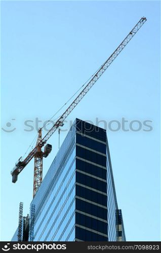 Crane and high-rise modern building under construction.
