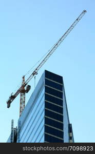 Crane and high-rise modern building under construction.