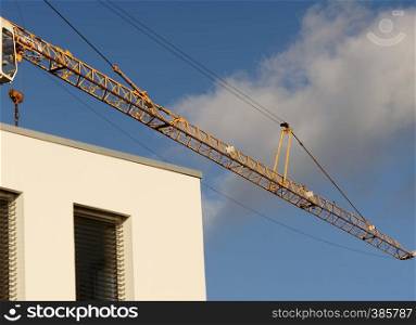 crane boom in front of a bright blue sky above the corner of a new building, abstract