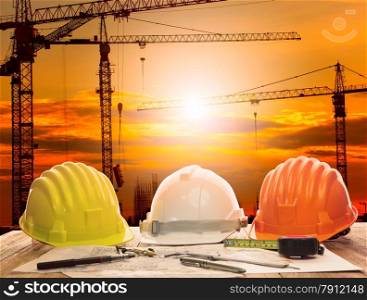 crane in construction site and working table of civil engineer with writing tool and plan of building