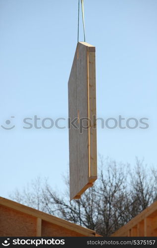 Crane lifting a wooden wall into place