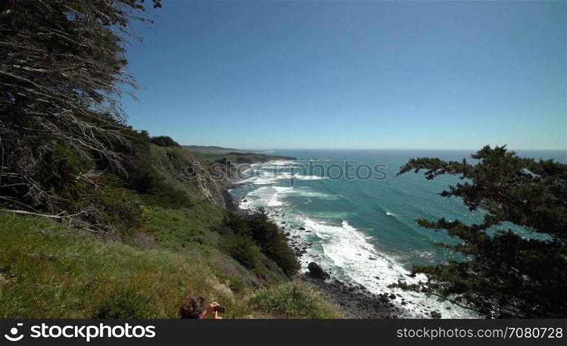 Crane shot of woman hiker photographing Big Sur coastline