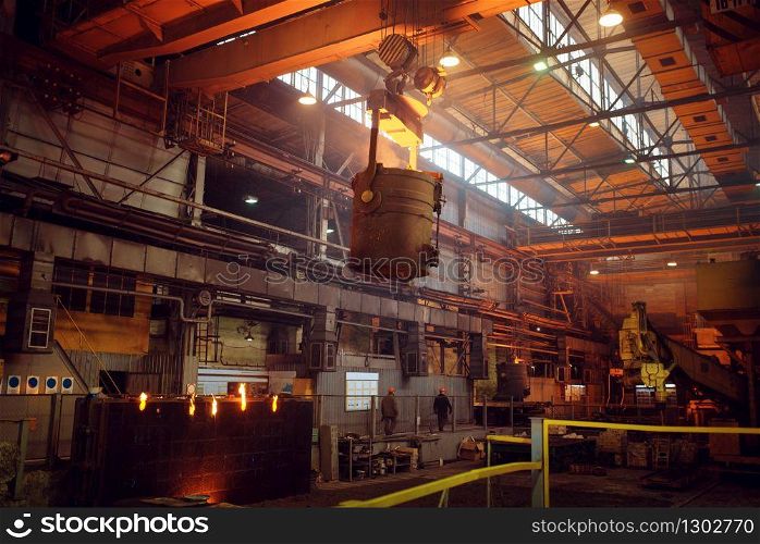 Crane with bucket of liquid metal on steel factory, metallurgical or metalworking industry, industrial manufacturing of production on mill. Crane with bucket of liquid metal on steel factory