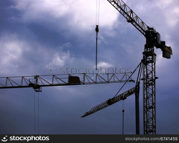 Cranes and rain clouds. Cranes at a construction site in front of rain clouds