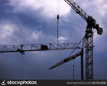 Cranes and rain clouds. Cranes at a construction site in front of rain clouds