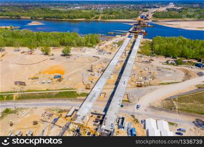 Cranes in the construction of a bridge for a highway. Aerial view